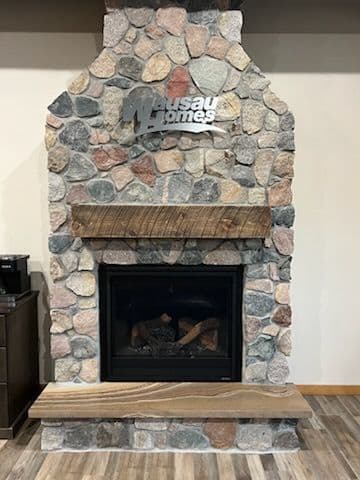 Stone fireplace with wooden mantel and decorative metal sign, enhancing cozy interior design.