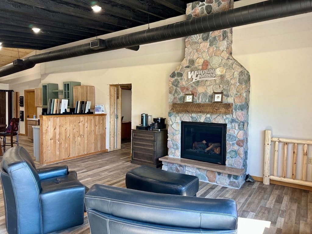 Modern living room with stone fireplace, black leather chairs, and wooden accents.