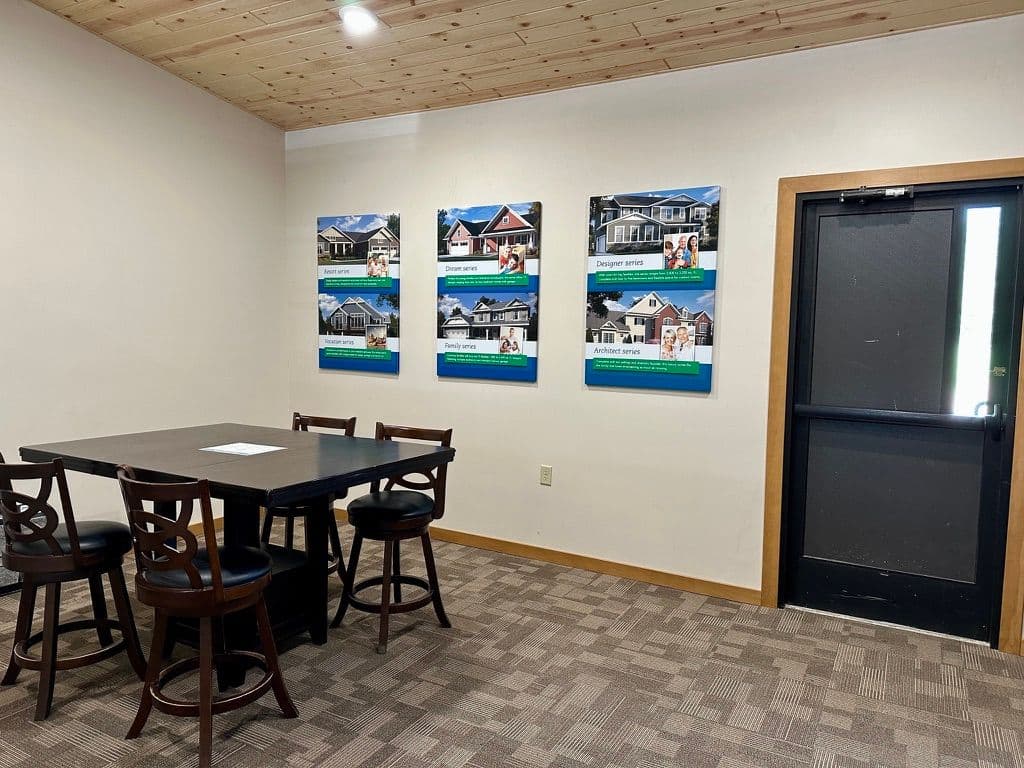 Meeting room with four framed home photos on the wall and a wooden table with chairs.