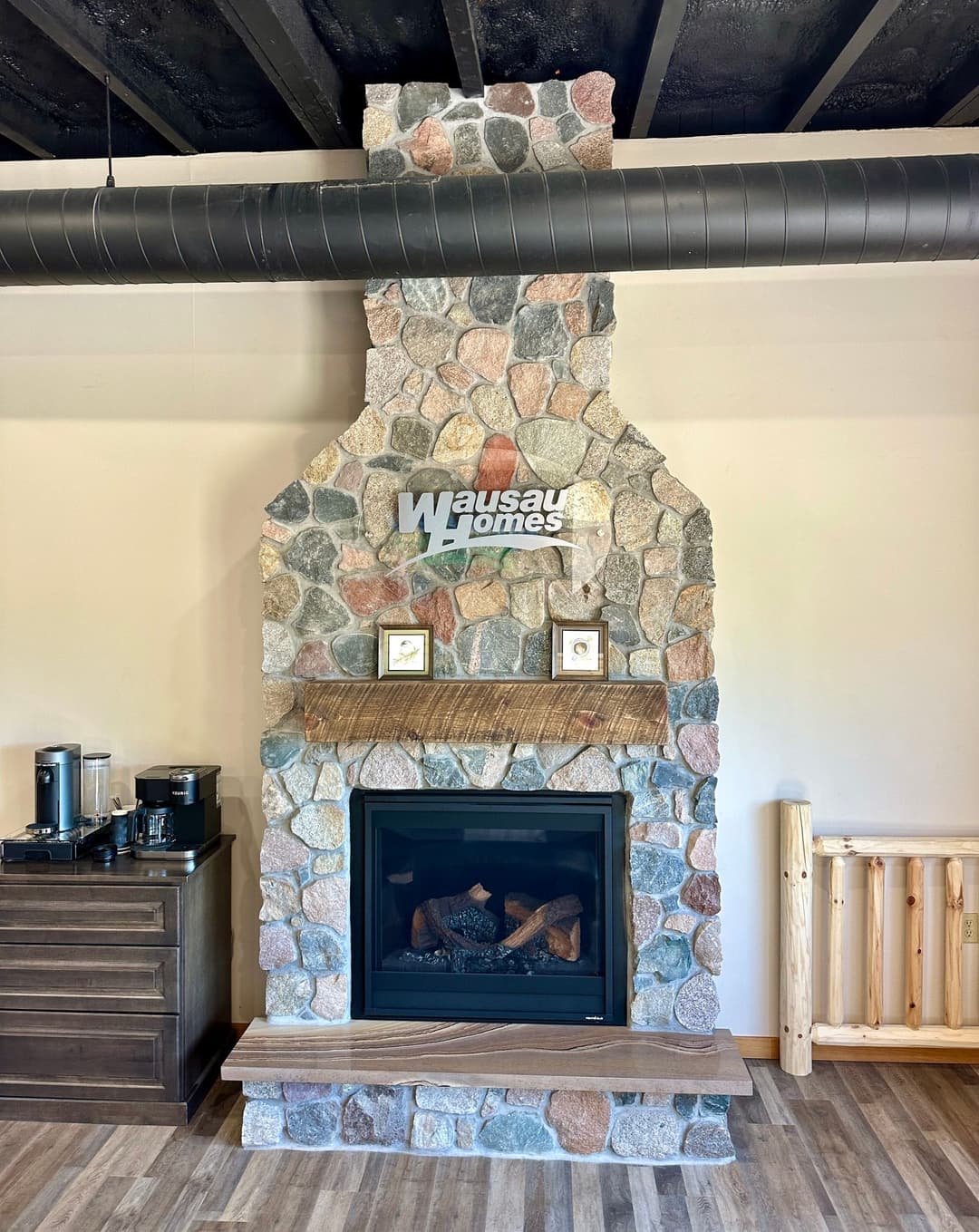 Stone fireplace with Wausau Homes logo in a modern interior setting.