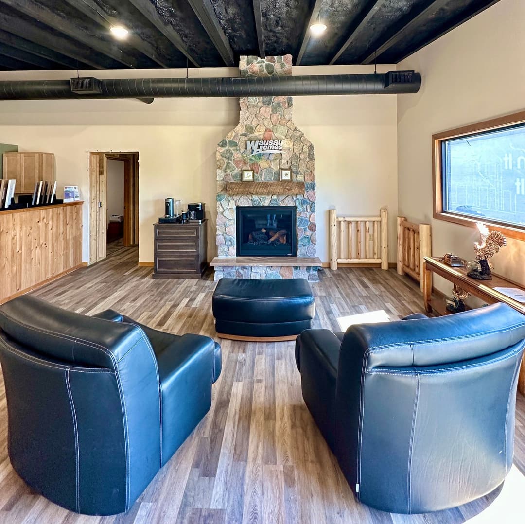 Cozy lounge with black leather chairs, stone fireplace, and wooden accents. Perfect for relaxation.